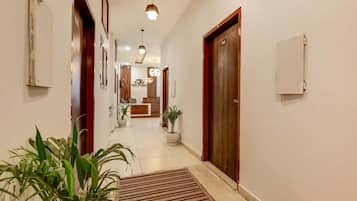 A hotel hallway with a reception desk, potted plants, and a reception area.
