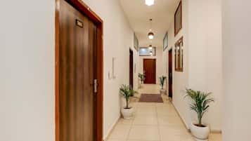 A hotel hallway with a wooden door labeled '201', potted plants, and a tiled floor.
