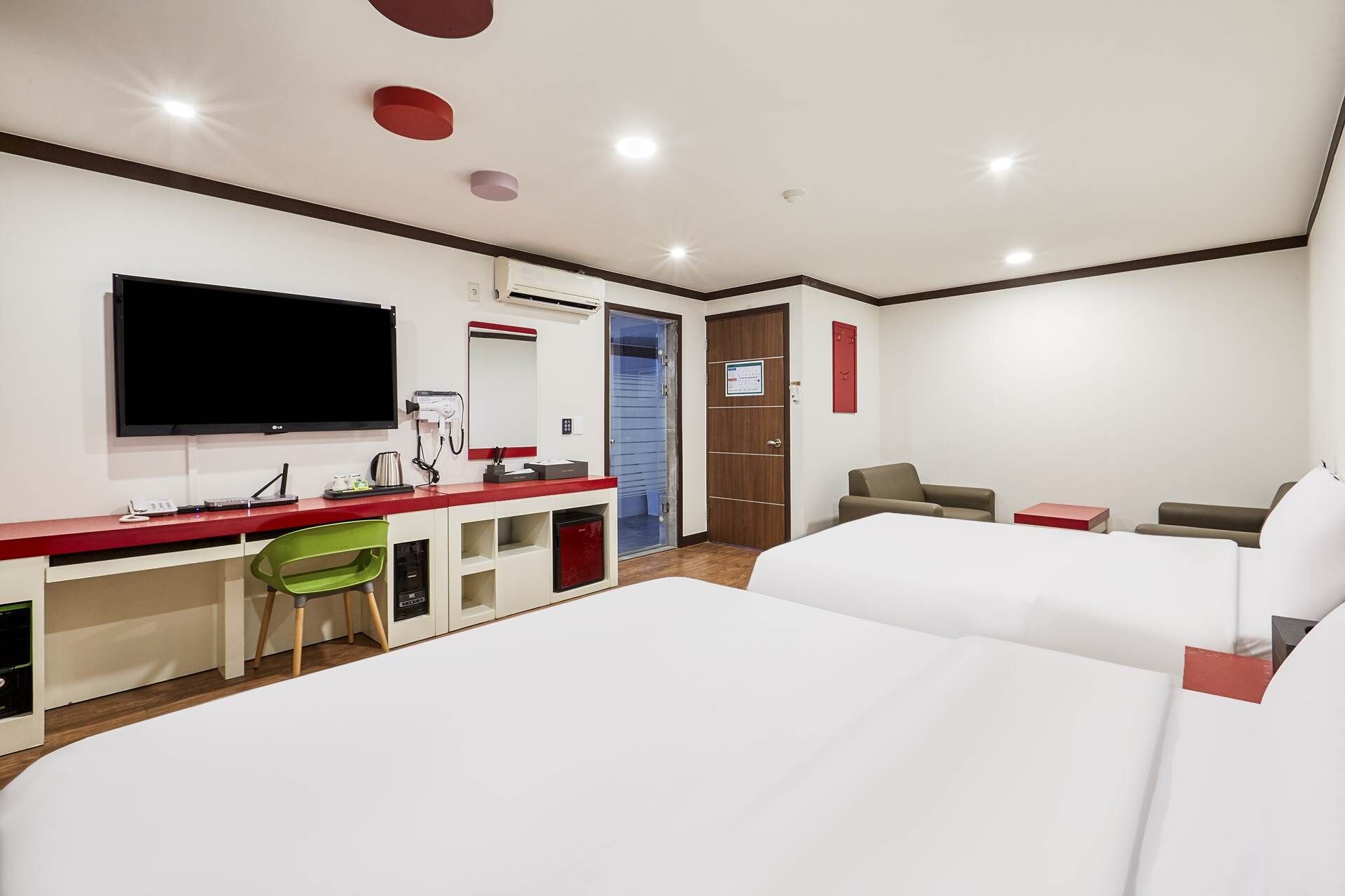 Una habitación de hotel con una cama, un escritorio con ordenador, televisor y espejo.
