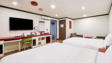 Una habitación de hotel con una cama, un escritorio con ordenador, televisor y espejo.