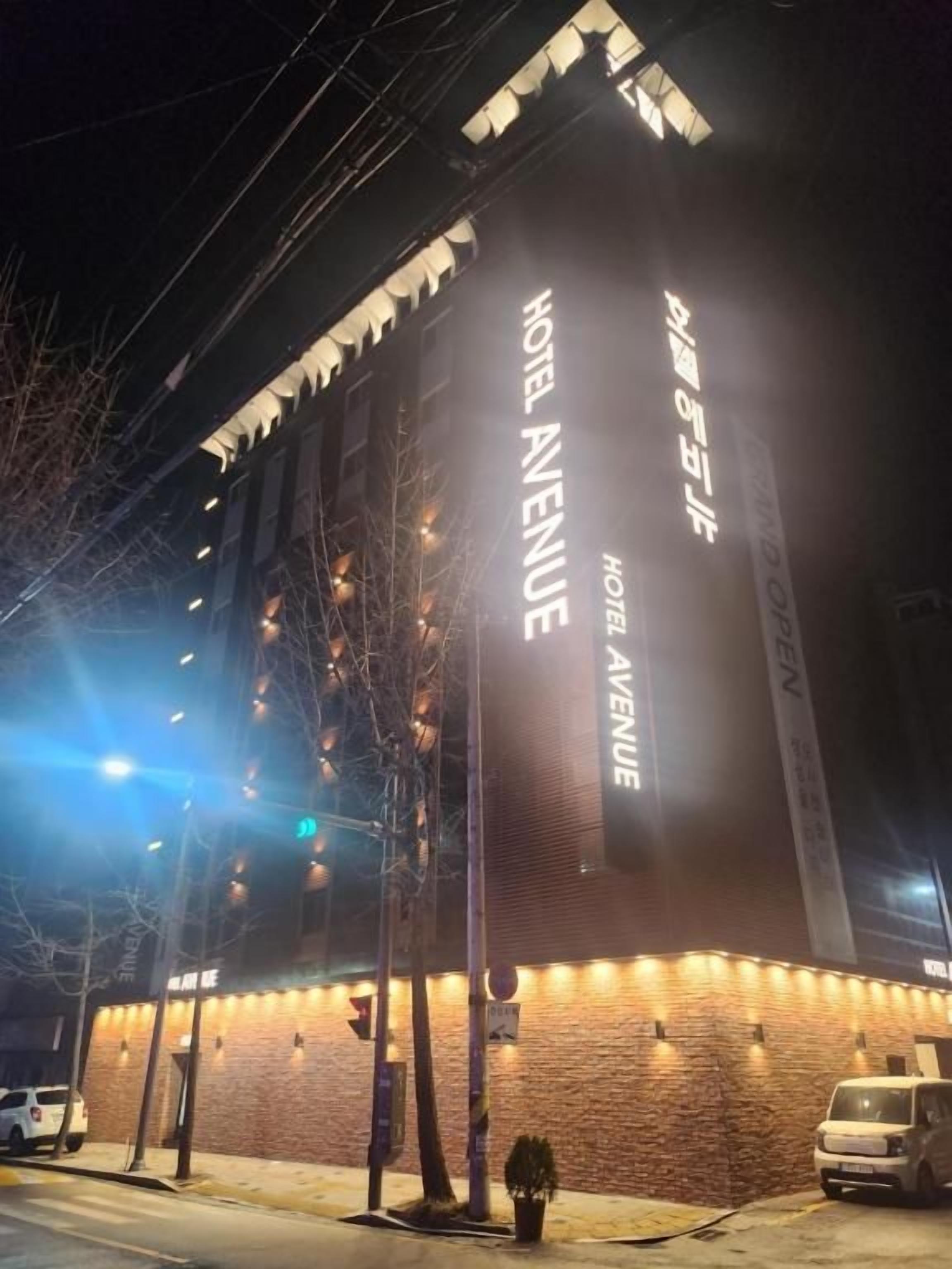 Un hotel con un letrero llamativo que dice 'HOTEL AVENUE' y una fachada de ladrillo.