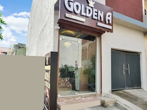 Entrada de un hotel con un letrero que dice 'GOLDEN A' y 'HABITACIONES DE LUJO'.