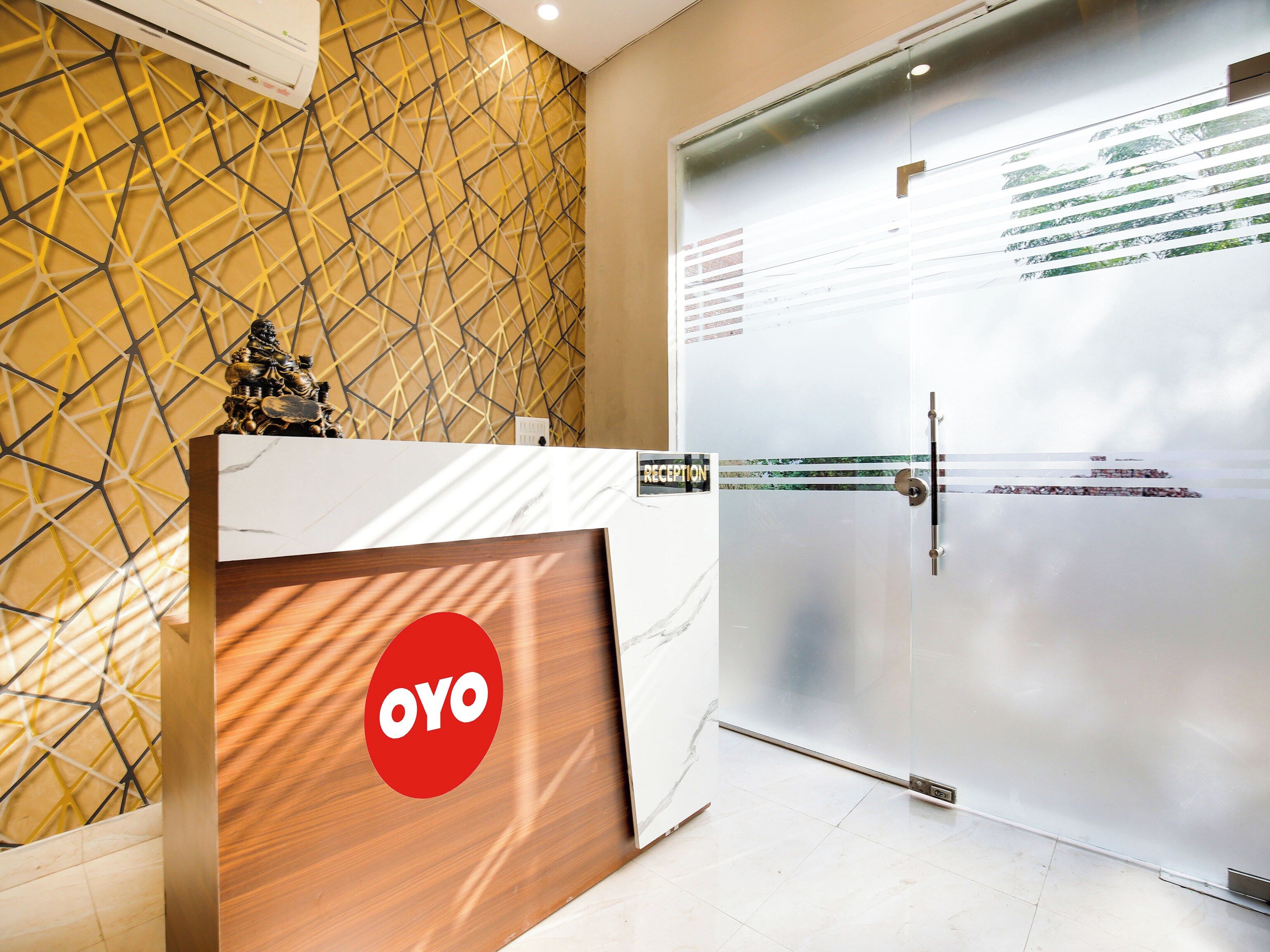 A reception area with a reception desk, a glass door, and a geometric patterned wall.