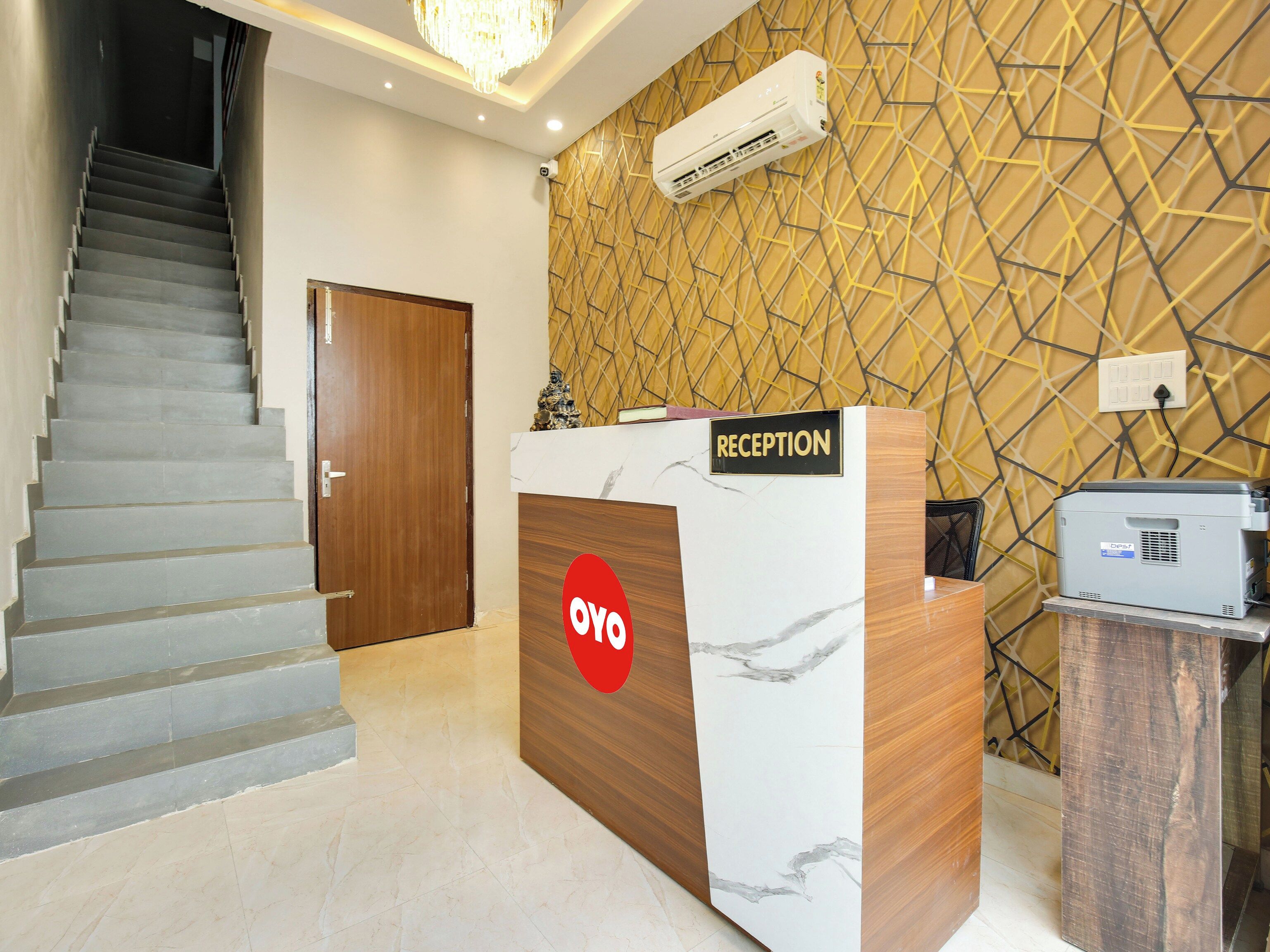 A reception desk with a marble design, a staircase, and a patterned wall.