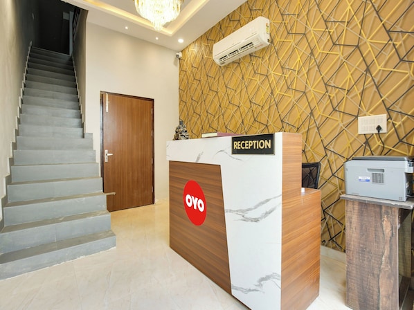 A reception desk with a marble design, a staircase, and a patterned wall. - Hotel O GOLDEN A (Ludhiana)