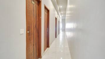 A corridor with wooden doors, white walls, and a tiled floor.