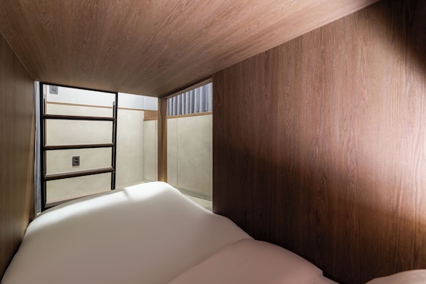 A room with a wooden ceiling, a bed with white bedding, and a window with blinds.