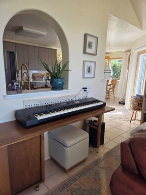 Ein Home-Office mit Tastatur, einem kleinen Hocker und einer Topfpflanze.