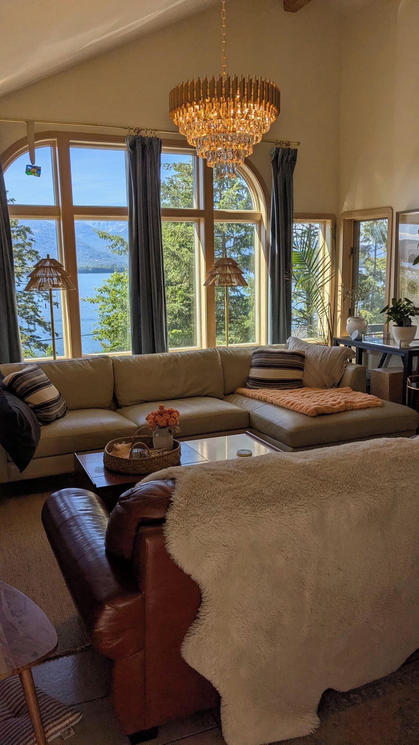 A spacious living room with a large window, a chandelier, and a sofa.