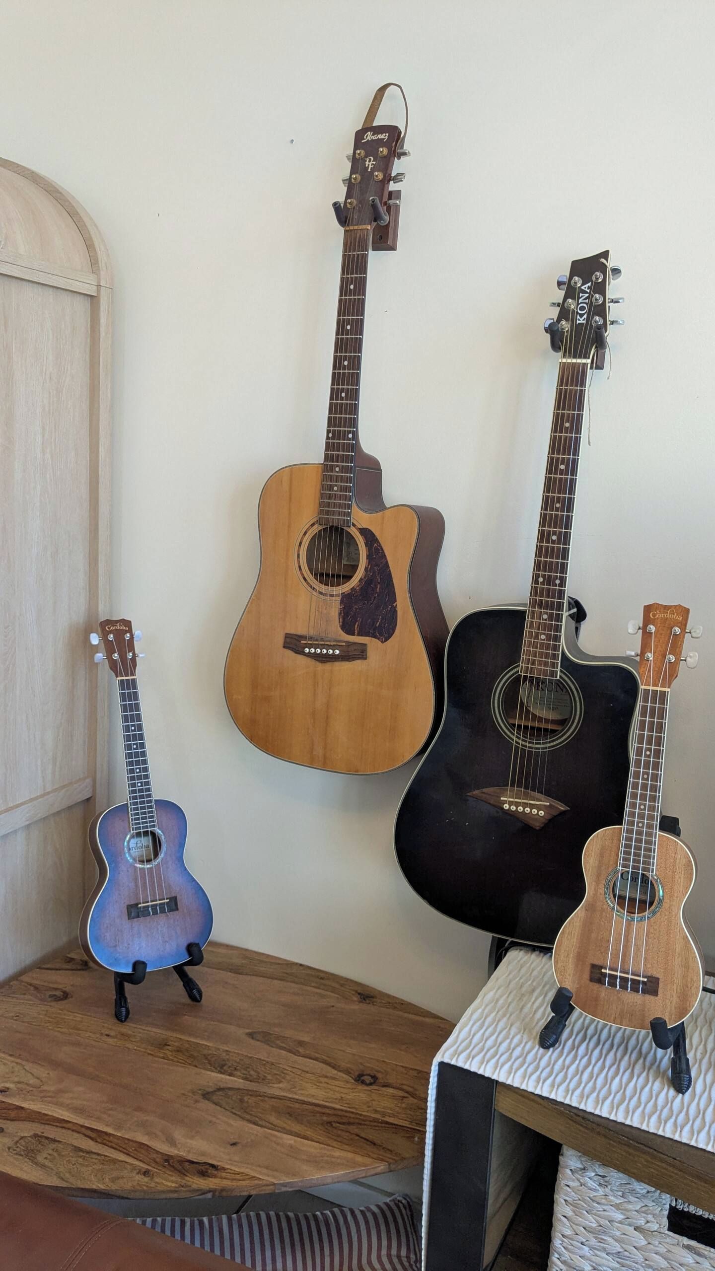 Four guitars of varying sizes and colors displayed against a wall.