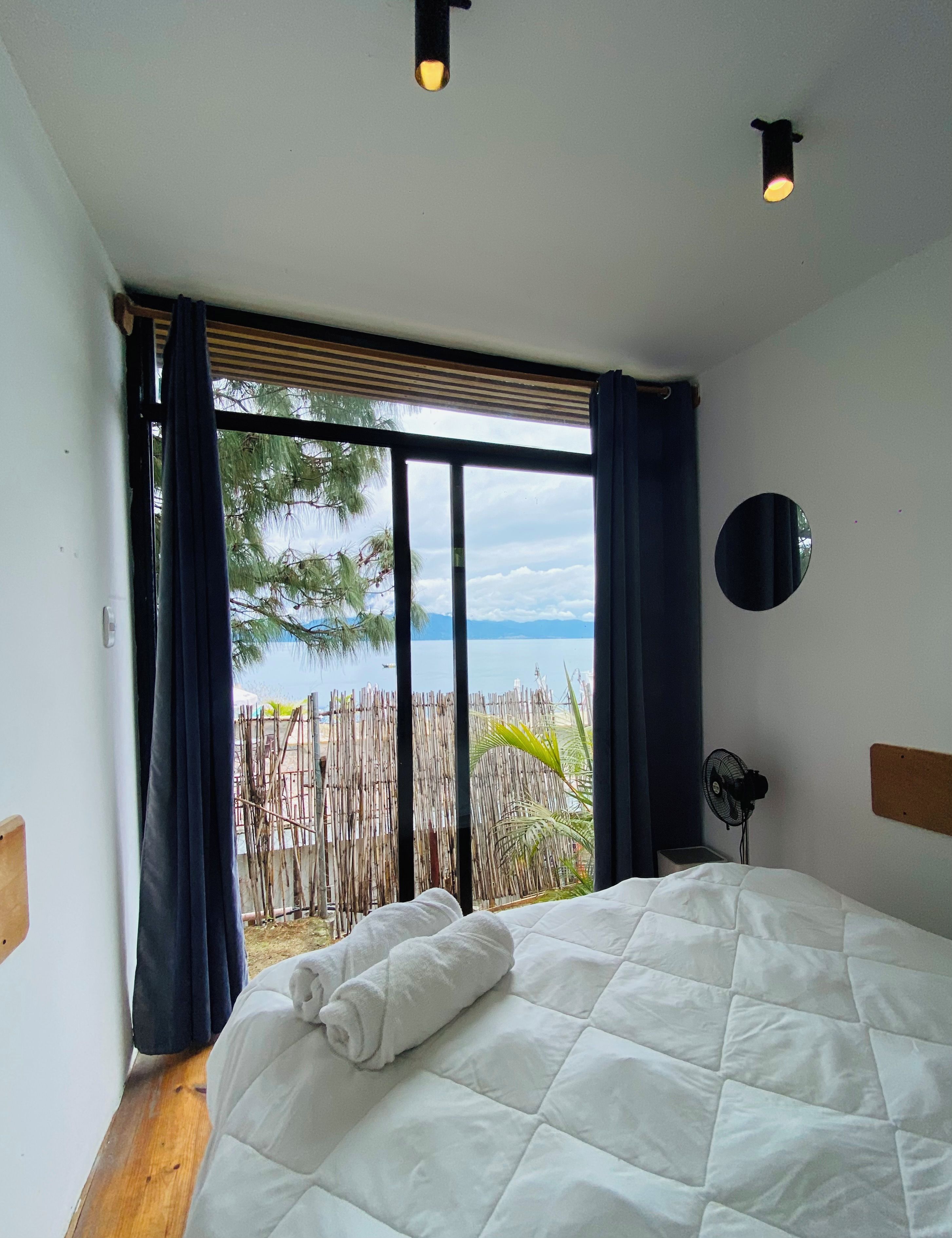 Un dormitorio con una cama grande, vistas al exterior y un ventilador de techo.