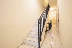 A staircase with a metal railing leading to a landing. - Tamastu House Grogol (Jakarta)