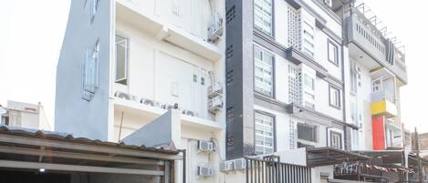 A multi-story building with balconies, air conditioning units, and a gated entrance.