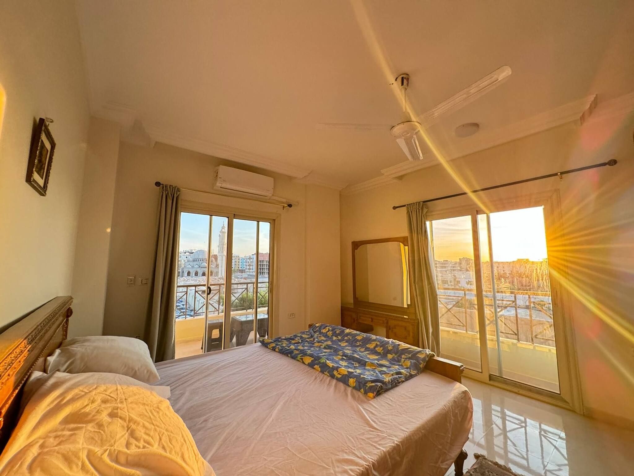 A bedroom with a bed, a window with a view, and an air conditioning unit.