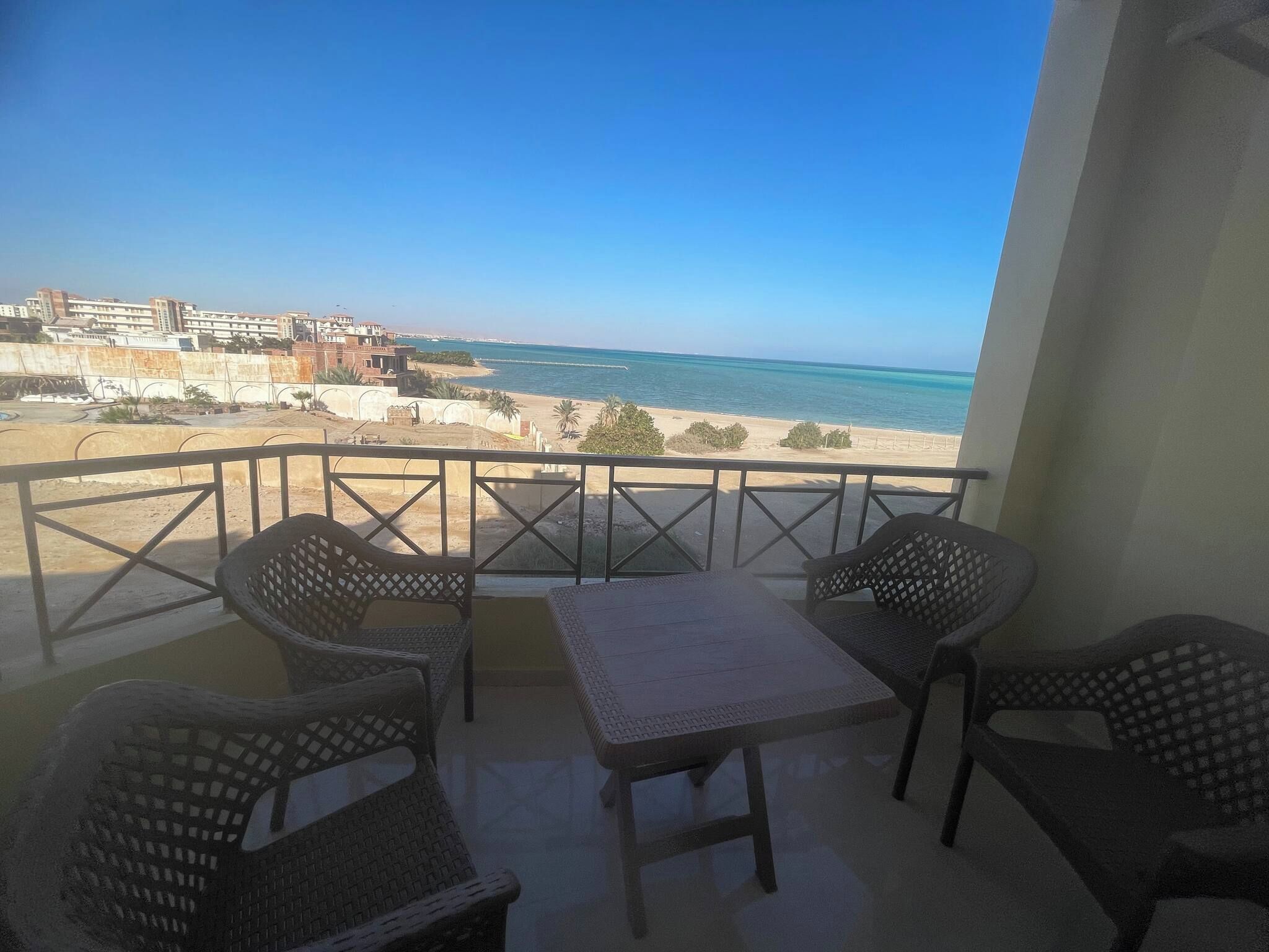 A balcony with a view of the beach and cityscape.