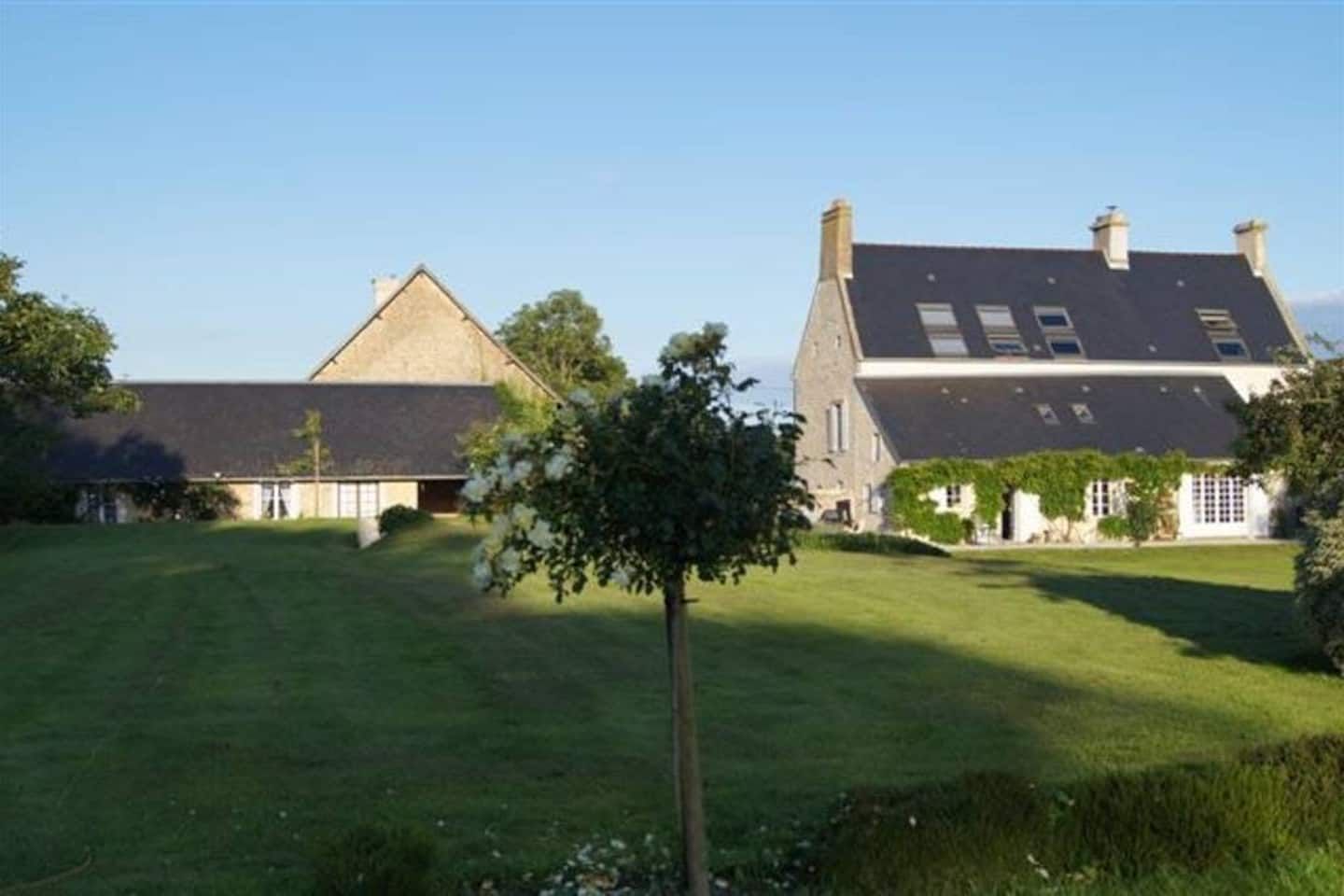 A large estate with a spacious lawn, a small tree, and two main buildings with pitched roofs.