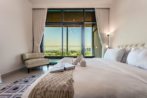 A hotel room with a large bed, a sofa, a view of the city, and a balcony. - HAVN - 1 Bed in Vista Prestige, Dubai Sports City (Dubai)