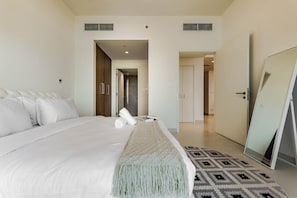 A hotel room with a large bed, a mirror, a patterned rug, and a wardrobe. - HAVN - 1 Bed in Vista Prestige, Dubai Sports City (Dubai)