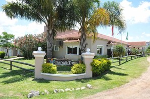Een Club Valle Terma resort met een bord, palmbomen en een omheind pad.