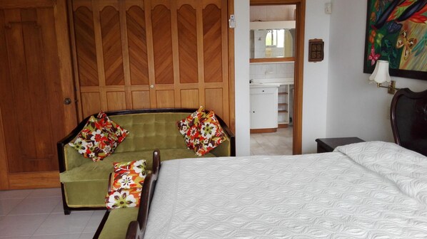 A room with a bed, a green armchair, a wooden wardrobe, and a mirror. - La Casa del Banquete (San Andrés)