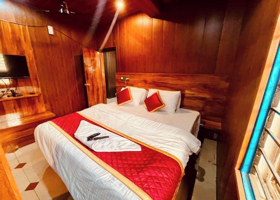 Una habitación con paneles de madera, una cama, un televisor y una mesita.