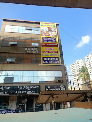 Un edificio de varios pisos con locales comerciales en la planta baja, que incluyen un restaurante y un servicio de reservas de habitaciones.