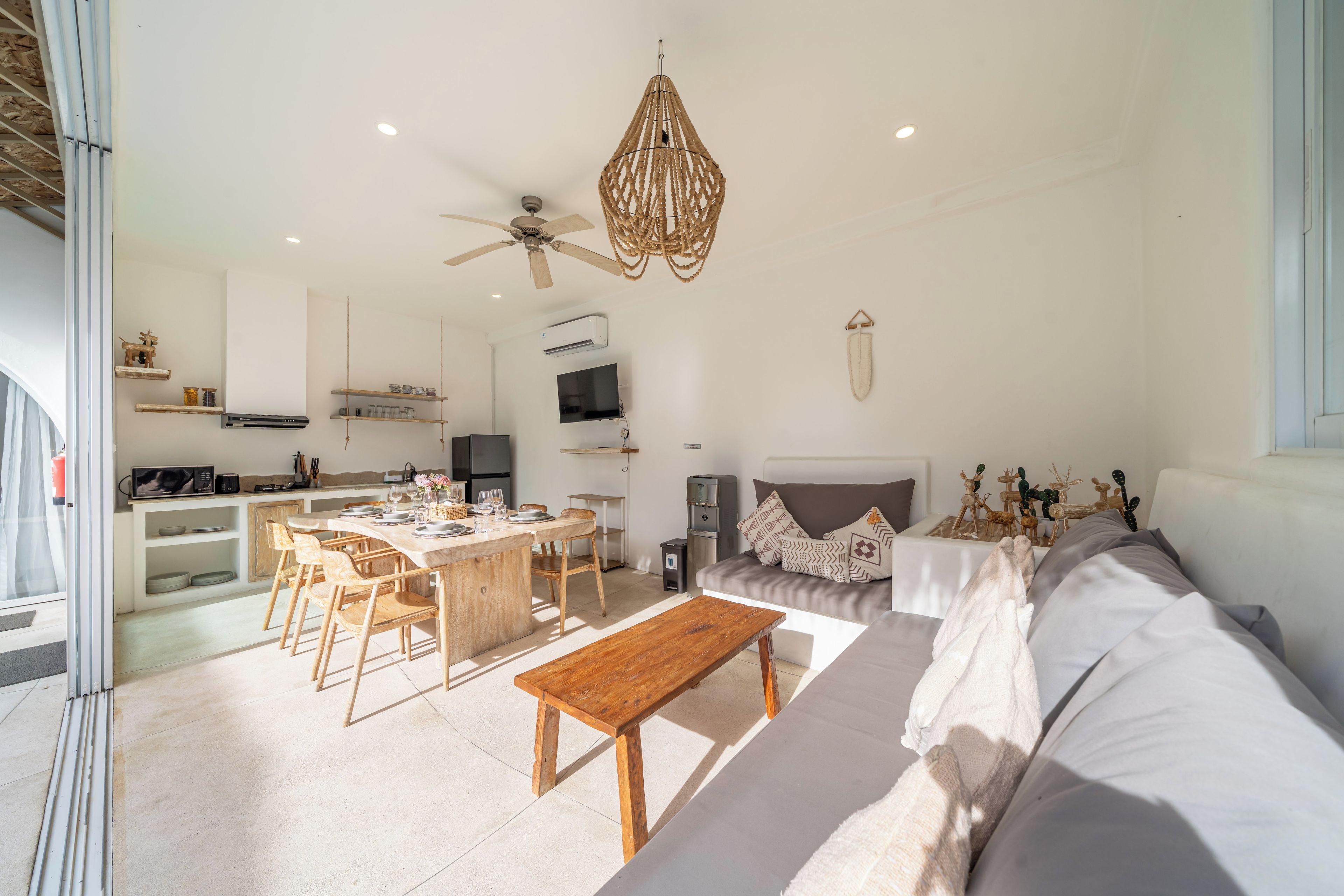 Una sala de estar moderna con comedor, ventilador de techo y dispensador de agua.