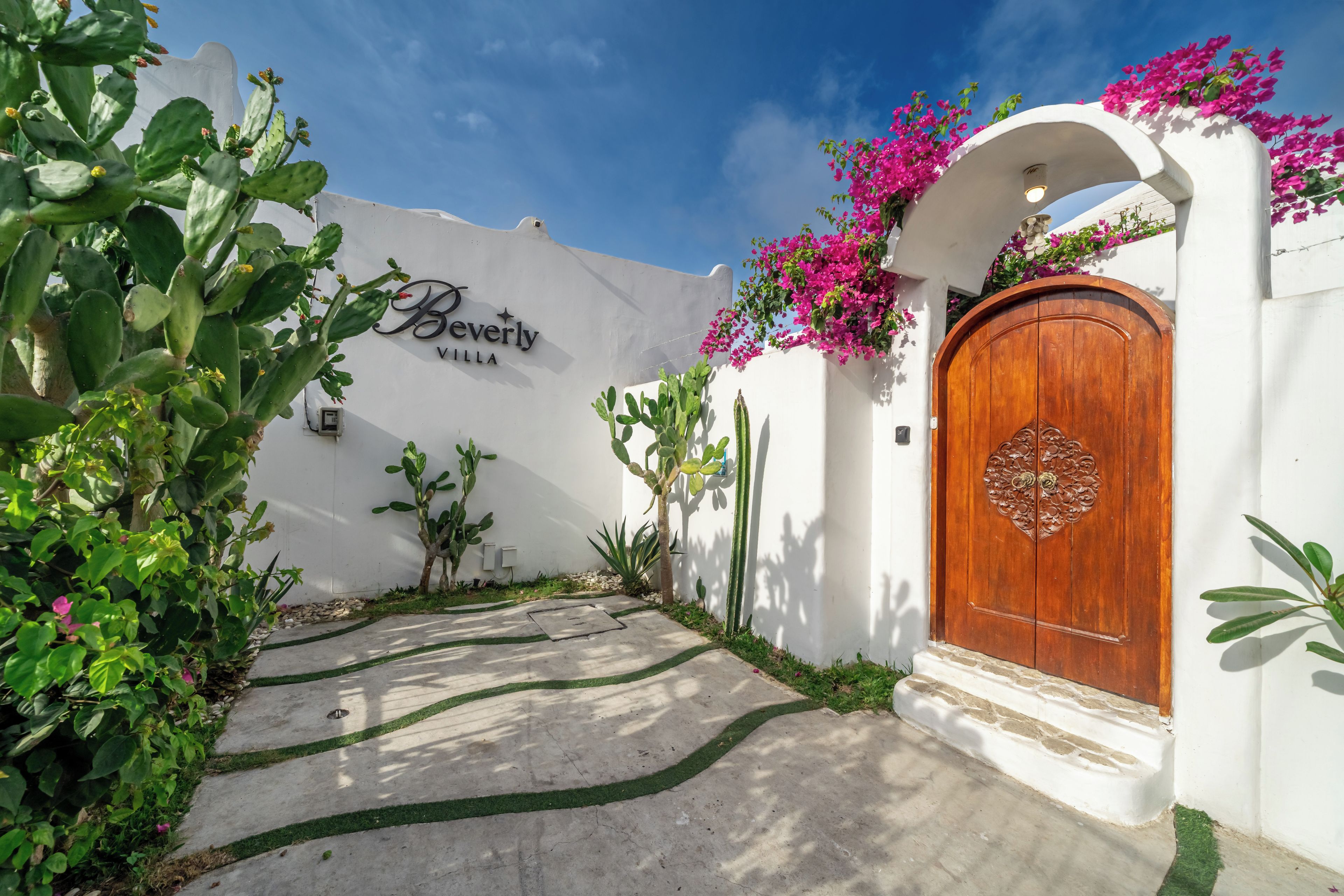 A white building with a wooden door and a sign that reads 'Beverly Villa.'