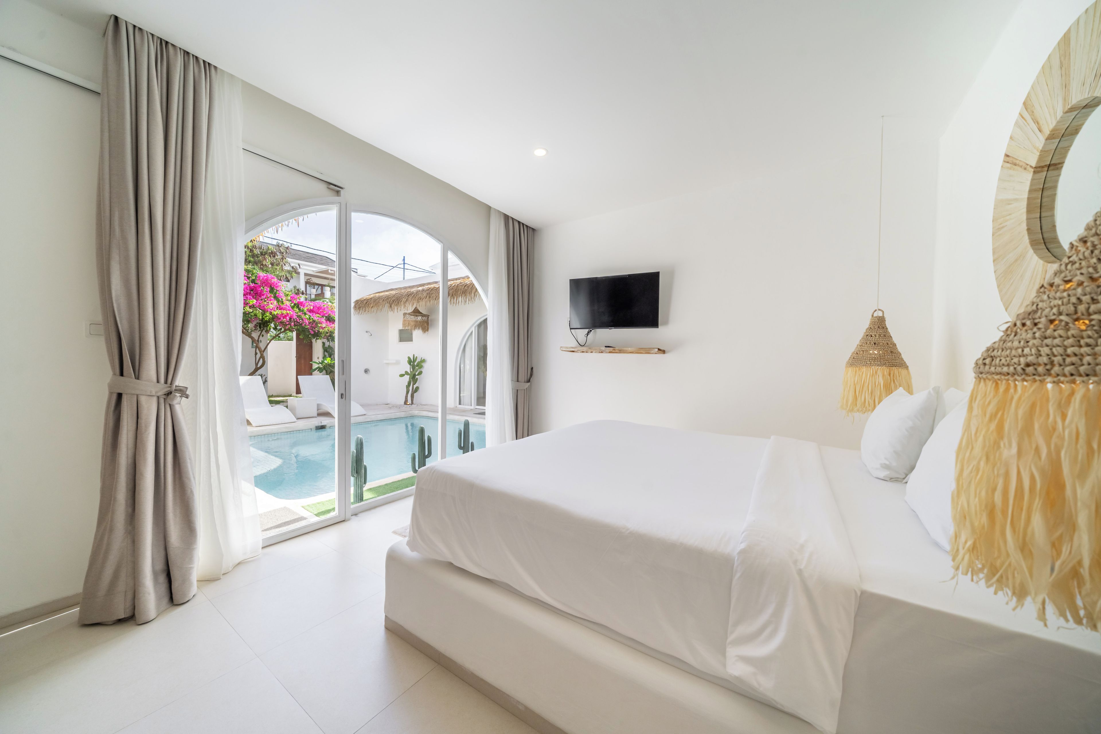 Ein Schlafzimmer mit einem großen Bett, einem an der Wand montierten Fernseher und Blick auf einen Pool im Freien.