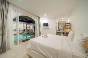 Habitación de hotel con cama, televisión, baño con espejo y zona de piscina.