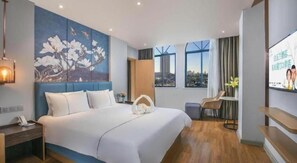 Une chambre d’hôtel avec un grand lit, un bureau, une chaise, une télévision et un tableau au mur.