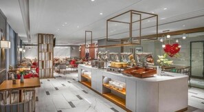 Un hall d’hôtel moderne avec un bar central, des espaces aménagés pour s’asseoir et une composition florale décorative.