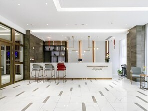 Un espace d’accueil moderne avec un sol en marbre, un comptoir de réception et des tabourets de bar.