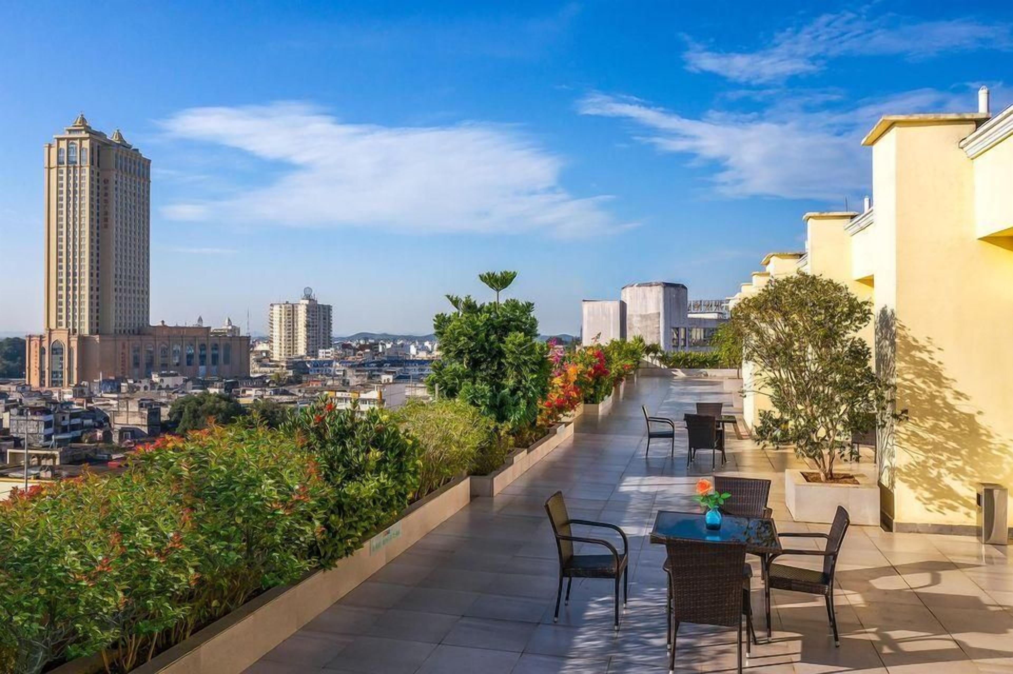 Une terrasse sur le toit offrant une vue sur le paysage urbain, avec notamment un immeuble de grande hauteur et d’autres bâtiments.
