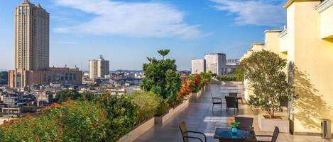A rooftop terrace with a view of the cityscape, including a tall building and other structures.