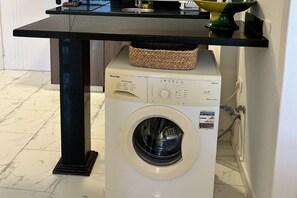 En frontbetjent vaskemaskine med kontrolpanel og en kurv ovenpå.