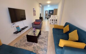 Un salon équipé d’un téléviseur à écran plat, d’un canapé, d’une table basse et d’un tapis à motifs.