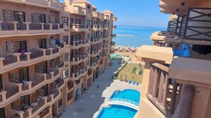 A multi-story hotel with balconies, a swimming pool, and a view of the sea. - Luxurious Chalet in Red Sea Governorate with Stunning Sea Views (Red Sea Governorate)
