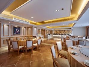 A spacious hotel dining area with multiple round tables and chairs, a central service counter, and a modern ceiling design. - Vienna International Hotel (Hangzhou)