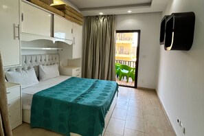 A bedroom with a bed, a wardrobe, a bedside table, a curtain, and a view of the outside. - Chalet with side sea and pool view, Turtles Beach (Hurghada 2)