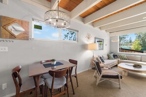 A dining area with a wooden table and chairs, a chandelier, and a view of the outdoors through a window. - Keys Boating Escape - 1BR Home (South Lake Tahoe)