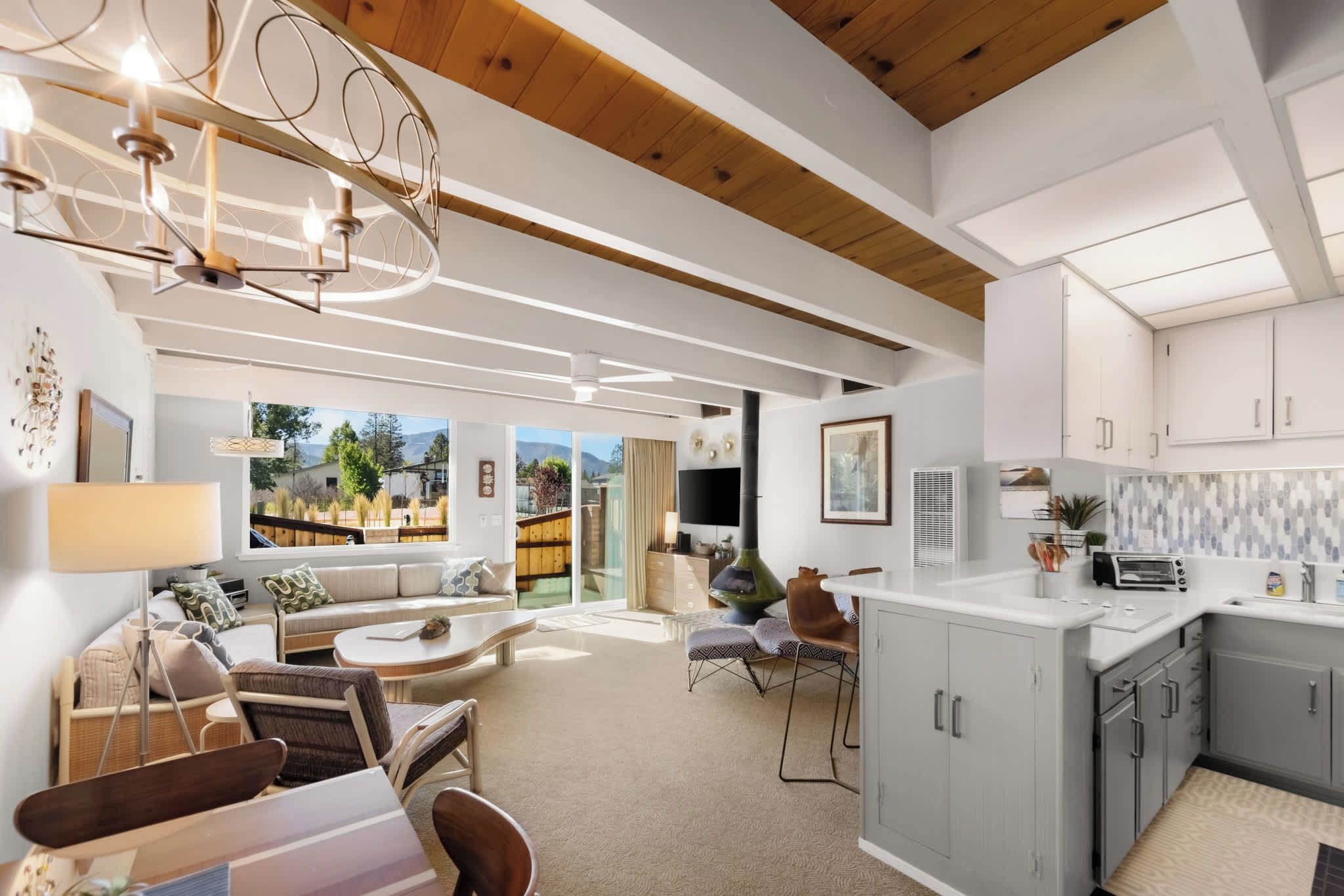 Un interior moderno con comedor, sofá, cocina y vistas al exterior.