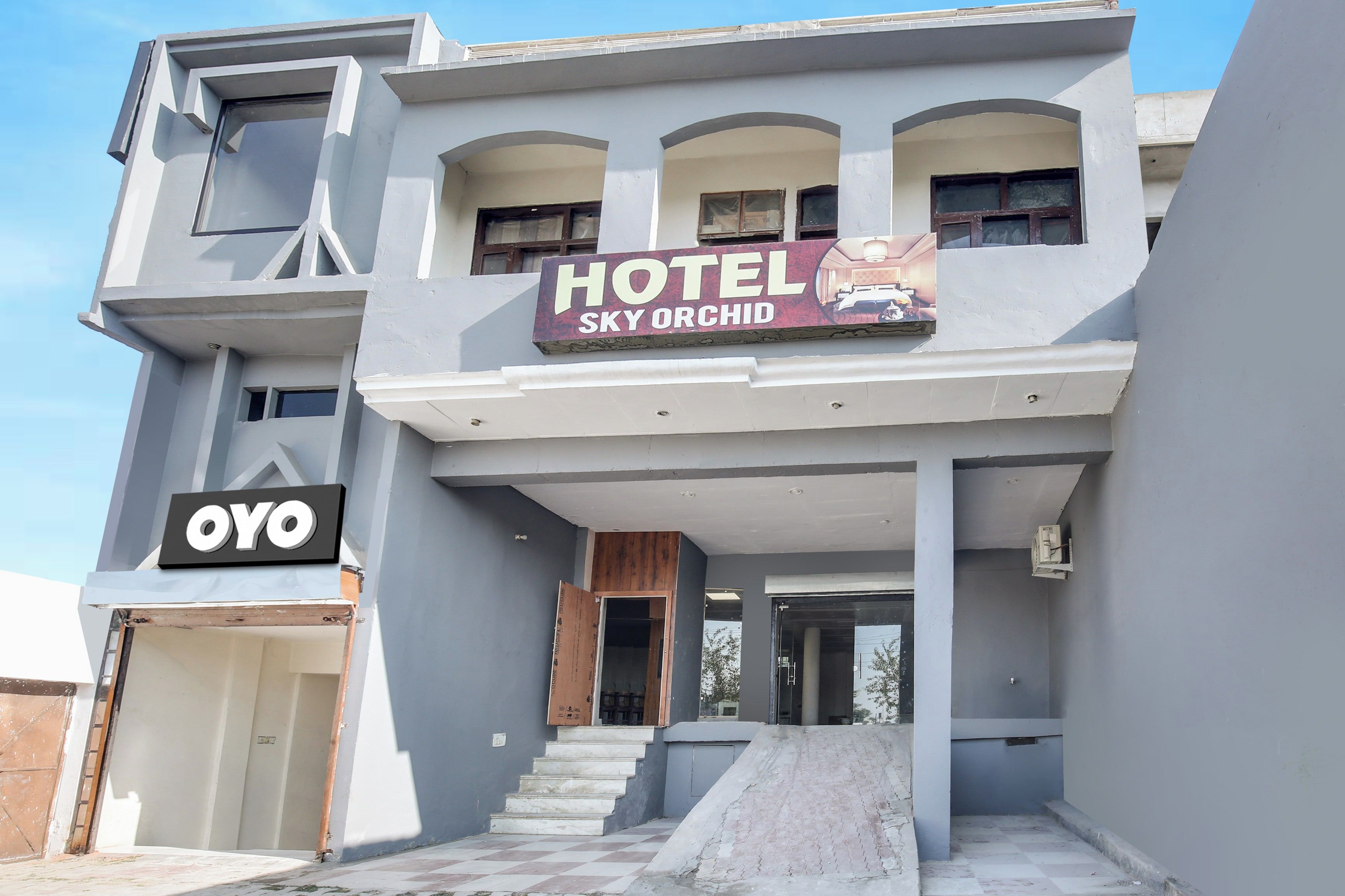 A hotel named 'Sky Orchid' with a modern architectural design, featuring a prominent entrance and a visible garage.