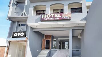 A hotel named 'Sky Orchid' with a modern architectural design, featuring a prominent entrance and a visible garage.