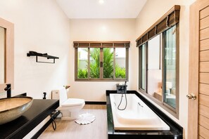 Un baño moderno con un ventanal grande, una bañera y un inodoro.