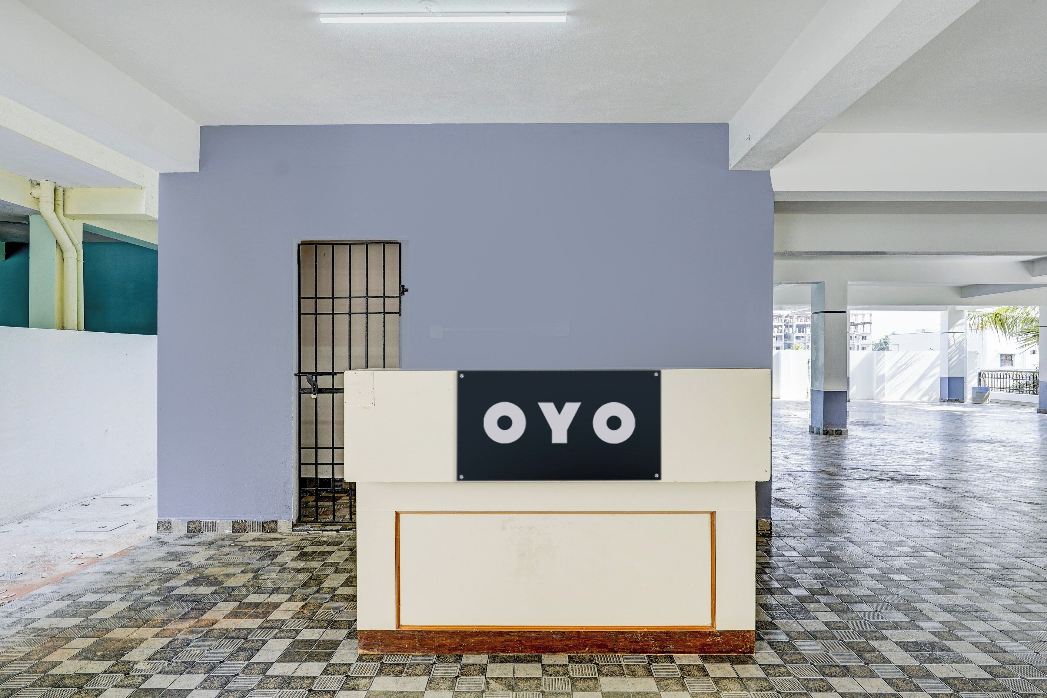 A room with a tiled floor, a door with a metal grid, and a sign with the word 'OYO' on a white background.