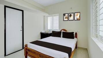 A bedroom with a wooden bed, a white door, a window with blinds, and two wall-mounted artworks.
