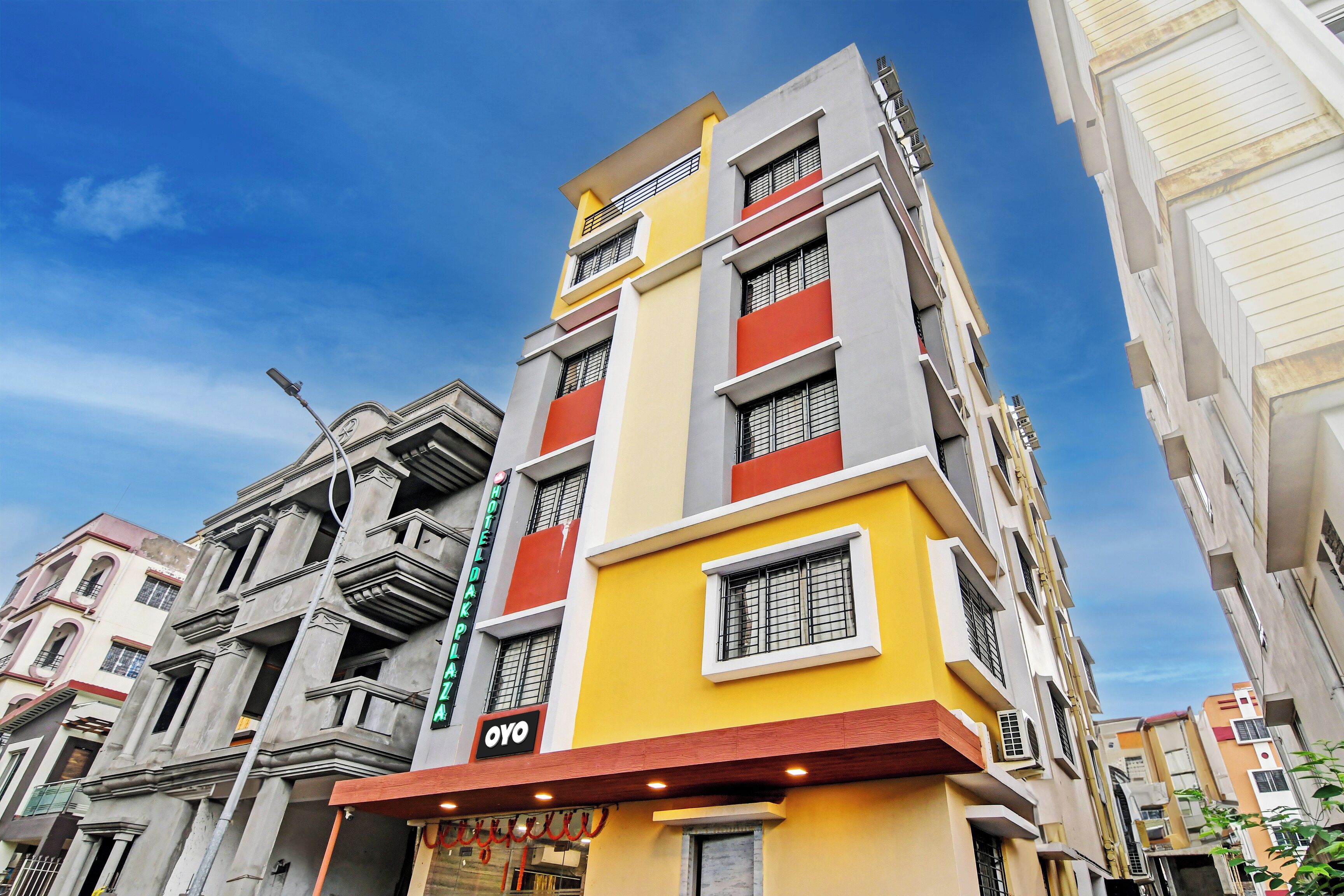 Un hotel de varios pisos con una fachada amarilla destacada, un letrero visible que dice 'HOTEL OYO' y un estilo arquitectónico tradicional con balcones.