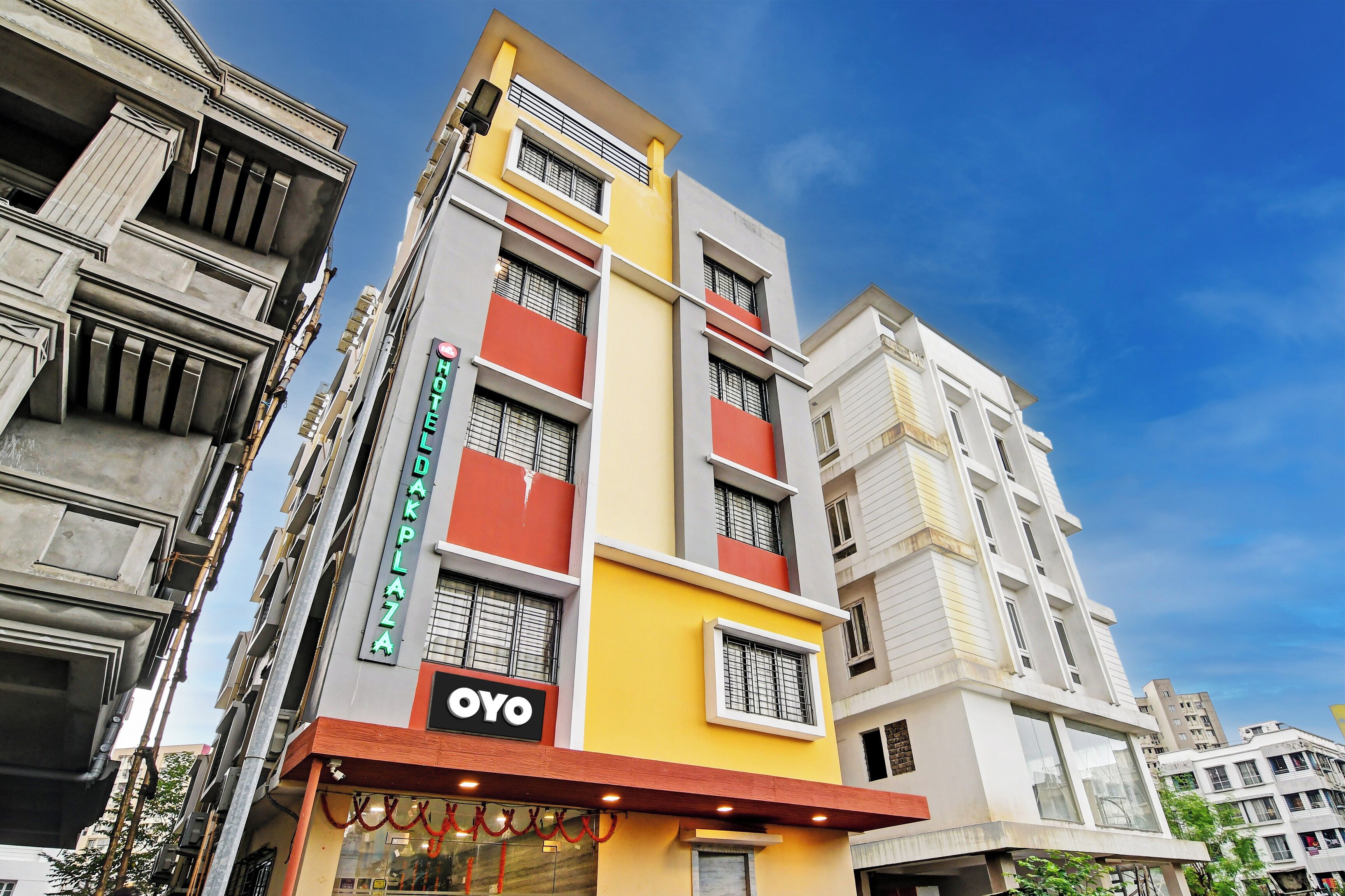 Un hotel de varios pisos con un llamativo letrero 'OYO', grandes ventanales y una fachada moderna.