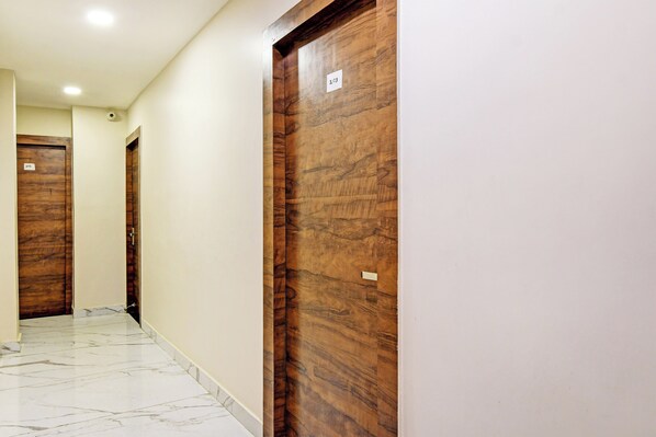A hallway with wooden doors, numbered 201 and 203, and a marble floor. - HotelO Dak Plaza Balaka Bus Terminus (Kolkata)